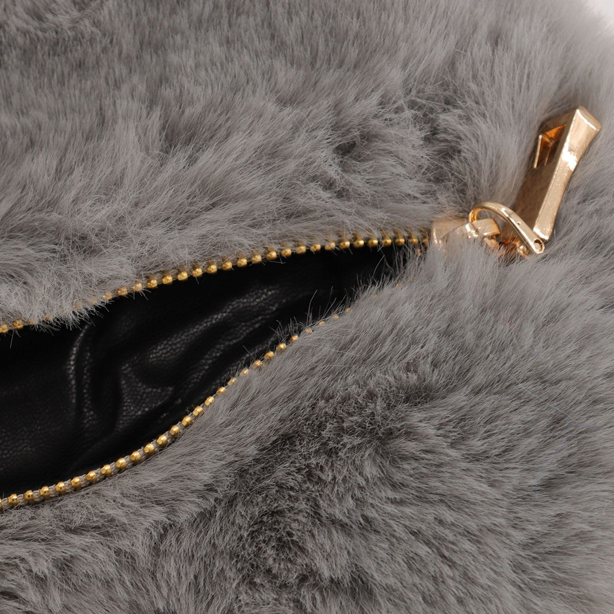 Close up of open gold zipper on grey faux fur heart bag.