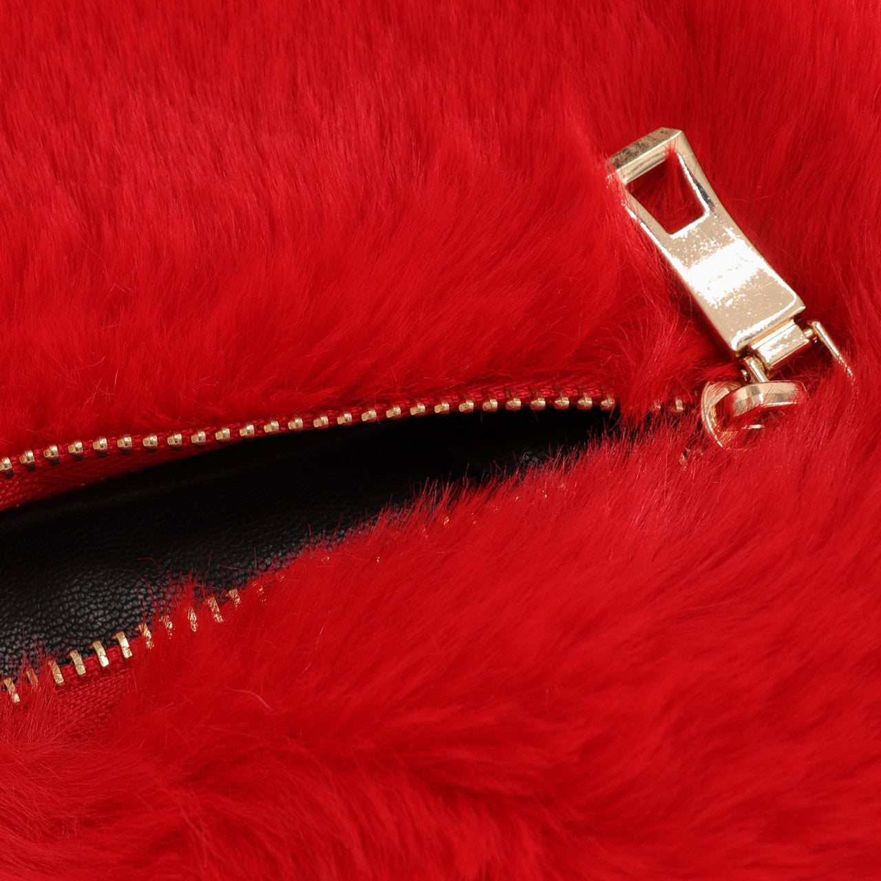 Close up of open gold zipper on red faux fur heart bag.