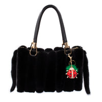 Bling Ladybug Keychain with Green Mink Pom hanging on the side of a black mink purse. 